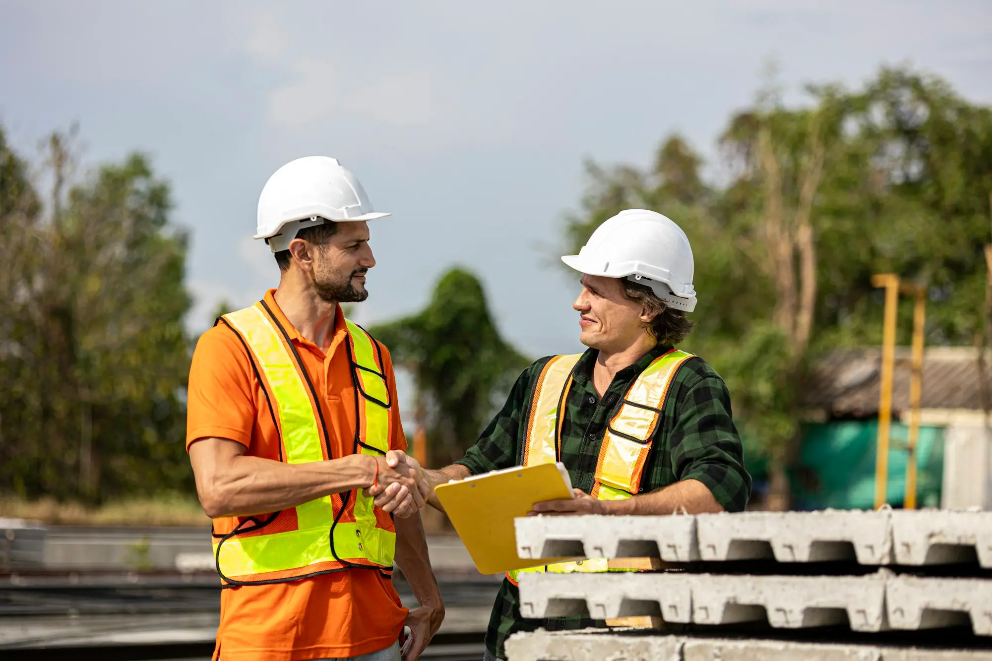 Construction workers in hi-vis shaking hands on site
